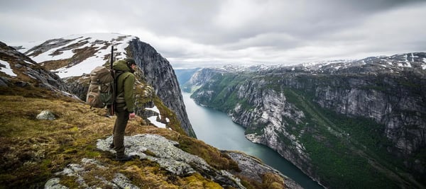 Jeger på toppen av et fjell ser ned på en fjord